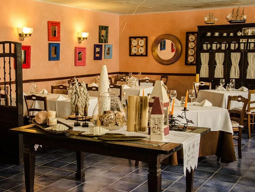 Une salle de restaurant aux murs chauds et aux tables nappées blanches.