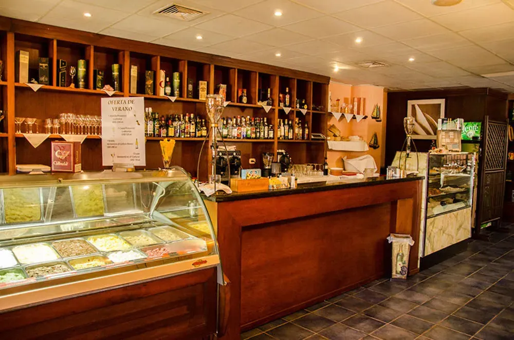 Un comptoir de bar en bois sombre présente des bouteilles et des verres.