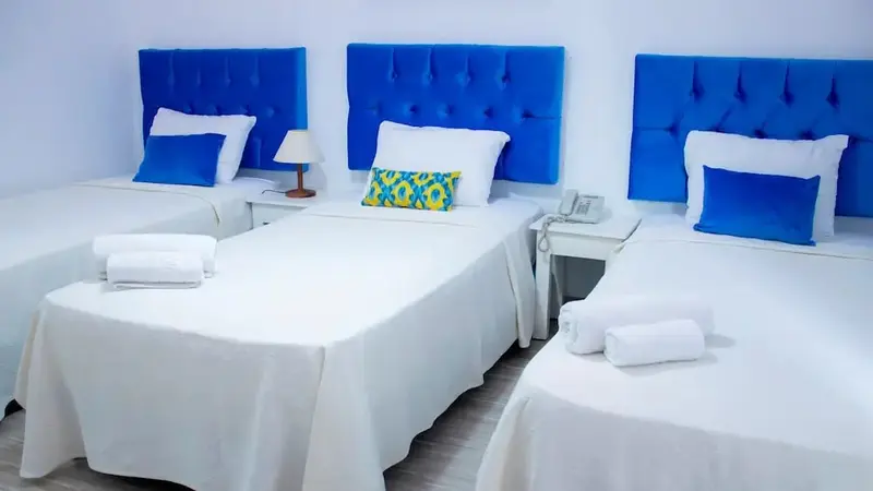 Trois lits simples dans une chambre lumineuse et minimaliste.