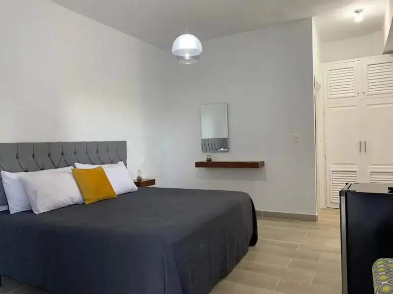 Une chambre lumineuse avec un grand lit et un miroir mural.