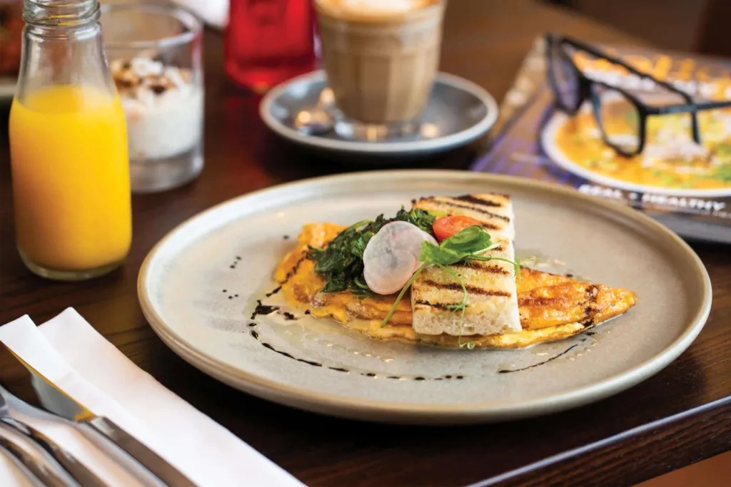 Une assiette d'omelette garnie est présentée avec une boisson et un dessert.