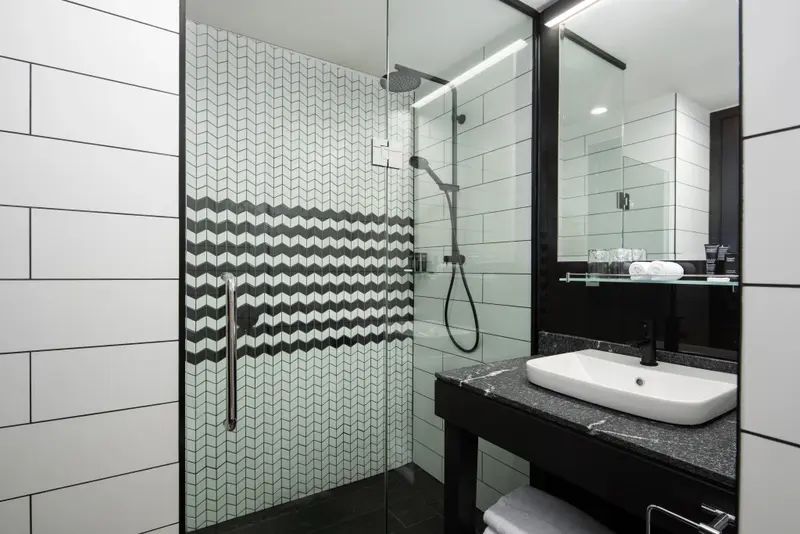 Une douche à l'italienne moderne avec des carreaux noirs et blancs et un lavabo sur un meuble sombre.