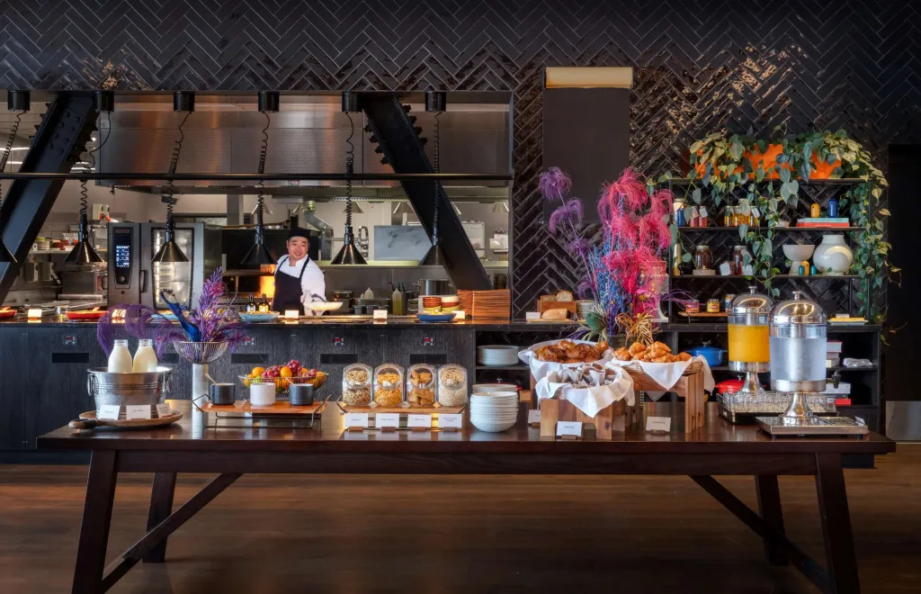 Un buffet propose des viennoiseries, des fruits et des boissons dans un espace lumineux.