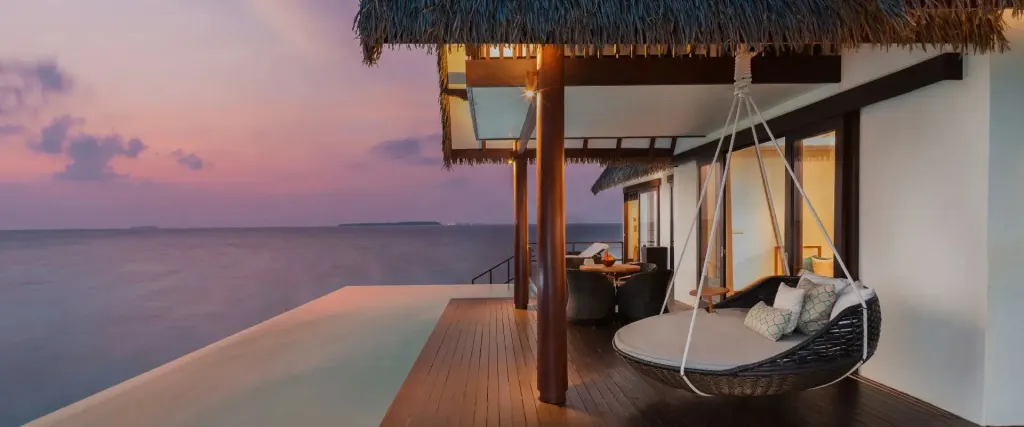 Terrasse en bois avec salon d'extérieur et vue sur la mer au coucher du soleil.
