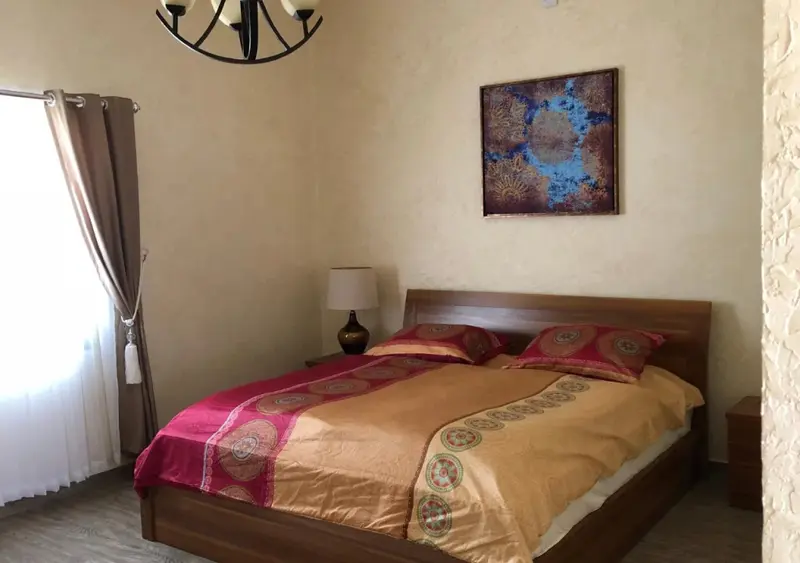 Une chambre lumineuse avec un grand lit recouvert d'une courtepointe colorée.