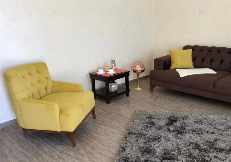 Un salon avec un fauteuil jaune et un canapé brun.