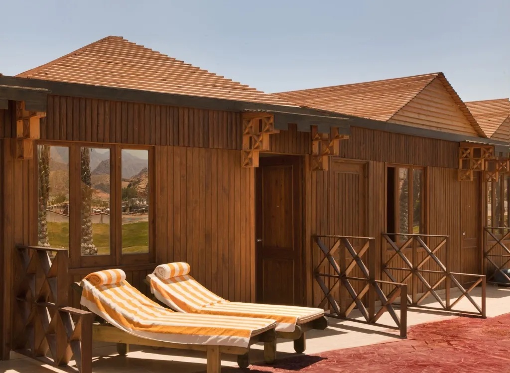 Deux transats colorés sont placés devant des bungalows en bois.