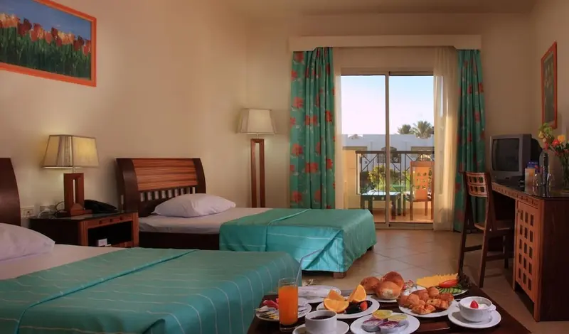 Une chambre lumineuse avec deux lits et une table basse servie pour le petit-déjeuner.