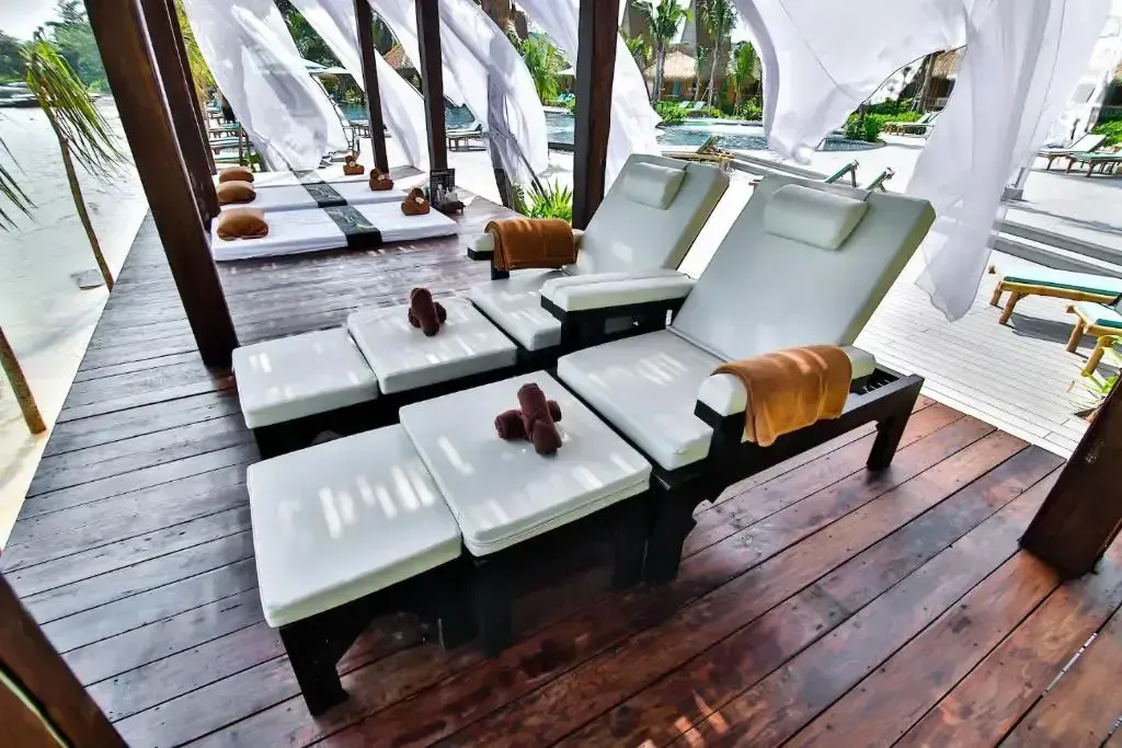 Transats blancs et bruns disposés sur une terrasse en bois ombragée.
