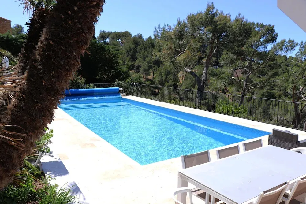 Une piscine rectangulaire bordée d'une terrasse ensoleillée.