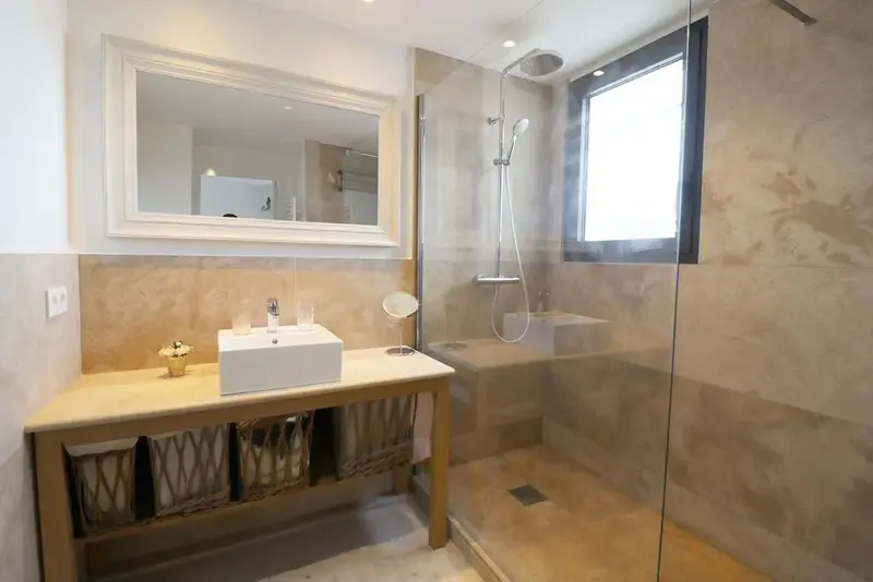 Une salle de bain lumineuse avec douche à l'italienne et vasque sur meuble.