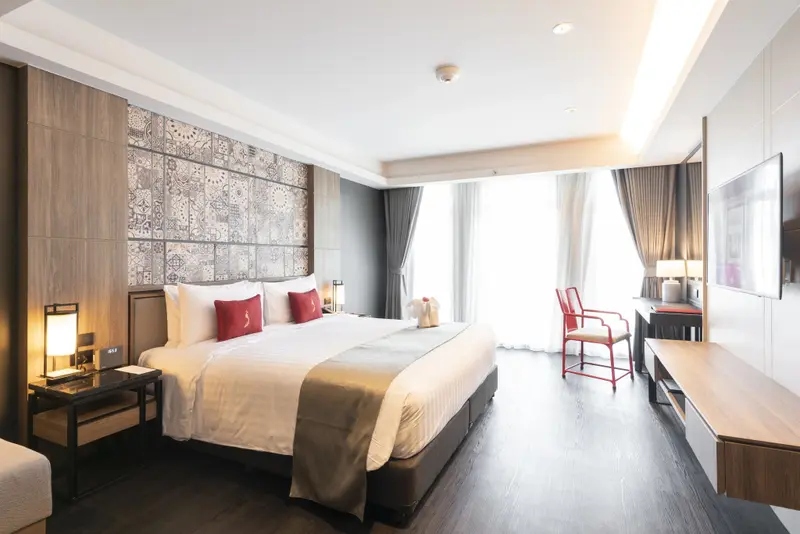 Une chambre lumineuse avec un grand lit et un coin lecture près de la fenêtre.