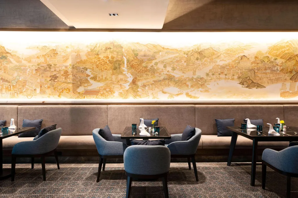Une salle de restaurant lumineuse avec des tables dressées et une grande peinture murale.