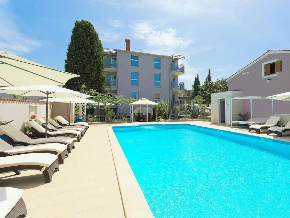 Transats et parasols bordent une piscine turquoise dans un espace extérieur ensoleillé.