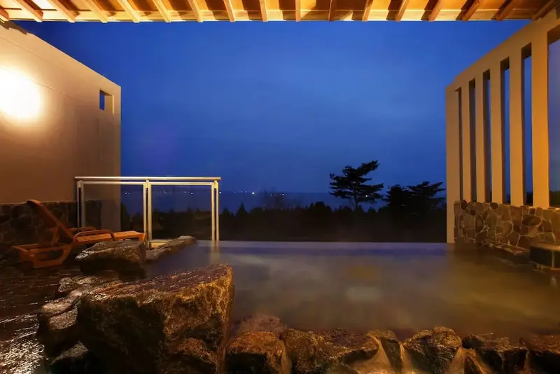 Bassin extérieur avec vue sur un paysage nocturne illuminé.