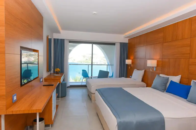 Une chambre lumineuse avec deux lits simples et une vue sur la mer.