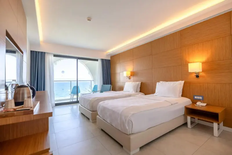 Chambre lumineuse avec deux lits simples et vue sur la mer.