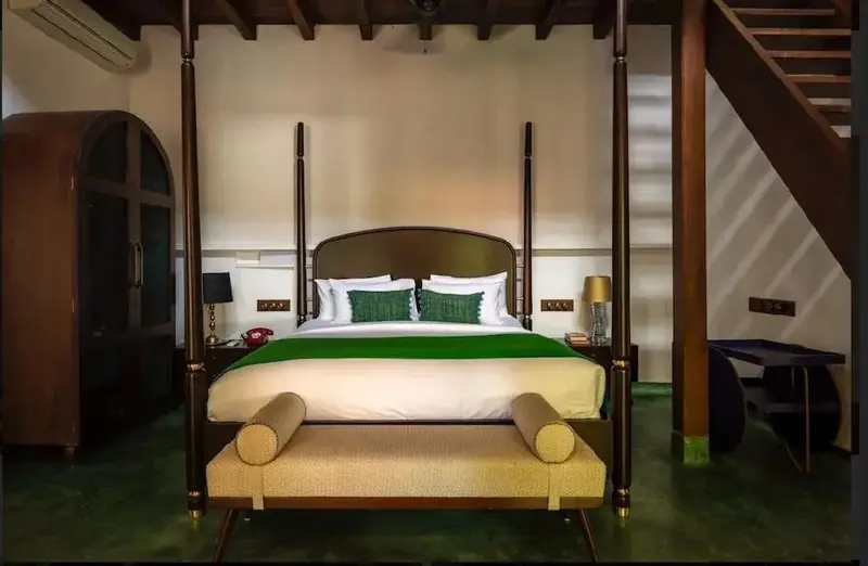 Un grand lit à baldaquin est disposé dans une chambre à l'ambiance chaleureuse.