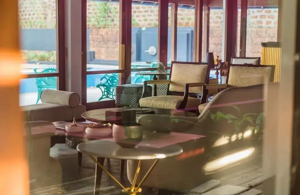 Un espace de détente intérieur avec des fauteuils et des tables basses près d'une piscine.