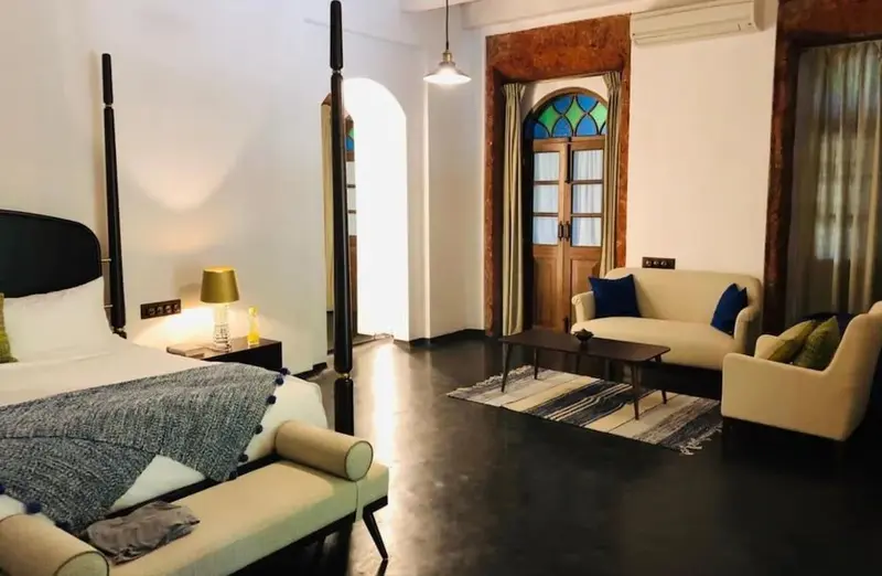 Une chambre lumineuse avec un grand lit et un coin salon.