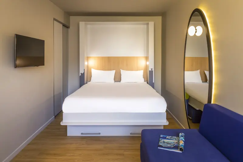 Une chambre moderne avec un grand lit et un miroir ovale.