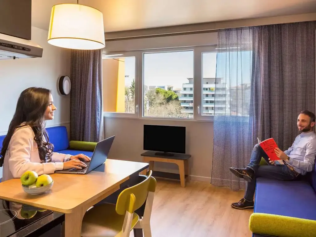 Un couple se détend dans un espace de vie lumineux avec un coin repas et un canapé.