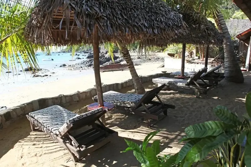 Transats ombragés sur une plage de sable fin.