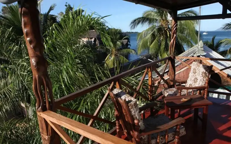 Terrasse en bois avec mobilier d'extérieur donnant sur la végétation et la mer.