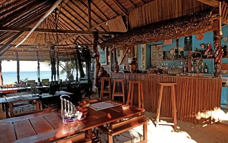Un bar en bois ouvert sur une plage ensoleillée.
