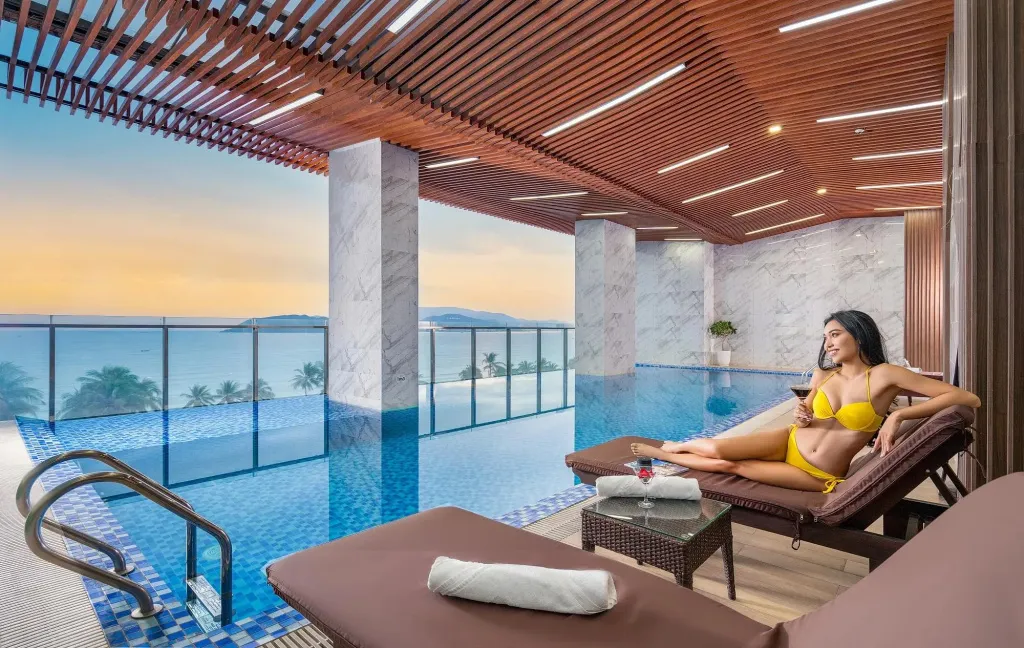 Une femme se détend au bord d'une piscine sur une terrasse avec vue sur la mer.
