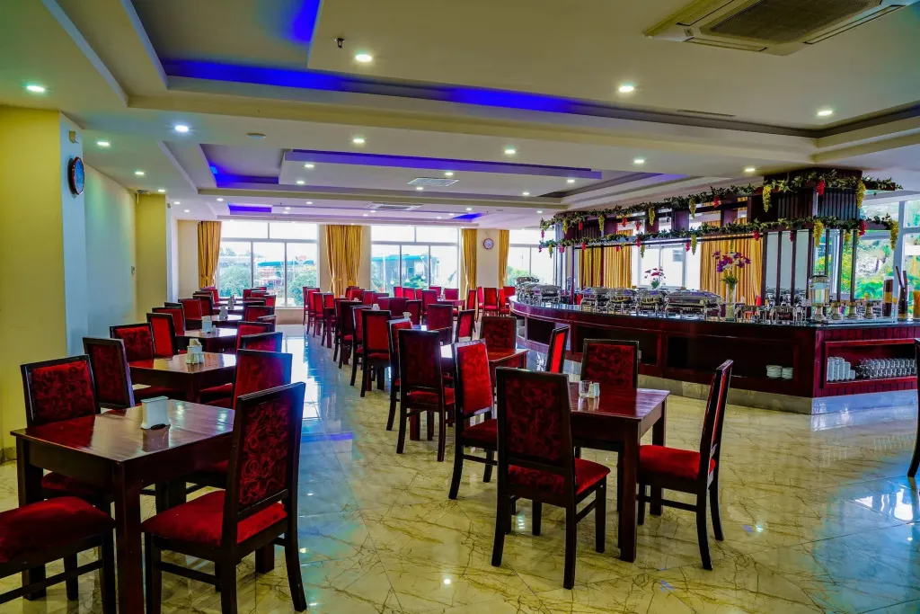 Une salle lumineuse avec des tables et des chaises, et un long comptoir de bar.
