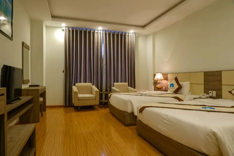Une chambre lumineuse avec deux lits simples et un fauteuil.