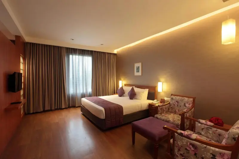 Une chambre lumineuse avec un grand lit et des fauteuils.