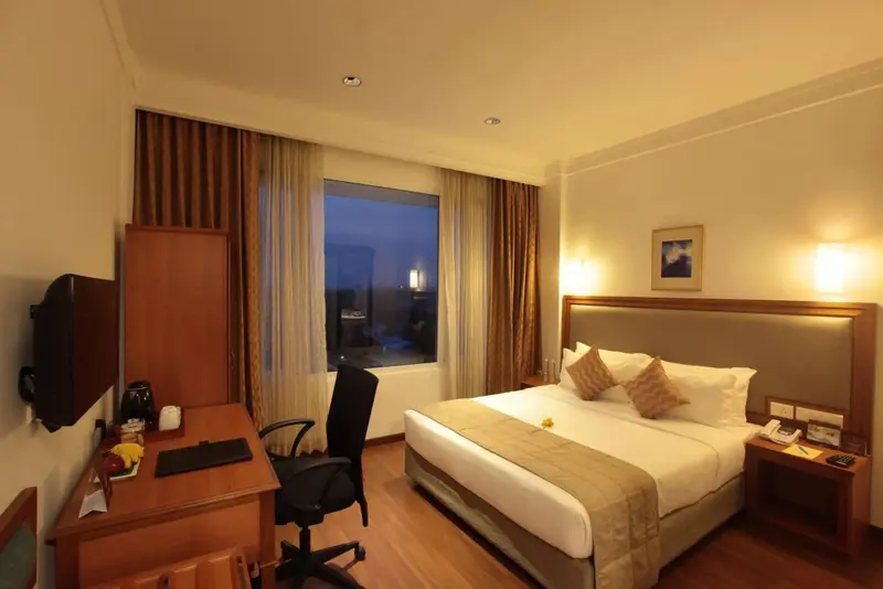 Une chambre d'hôtel lumineuse avec un grand lit et un bureau près d'une fenêtre.