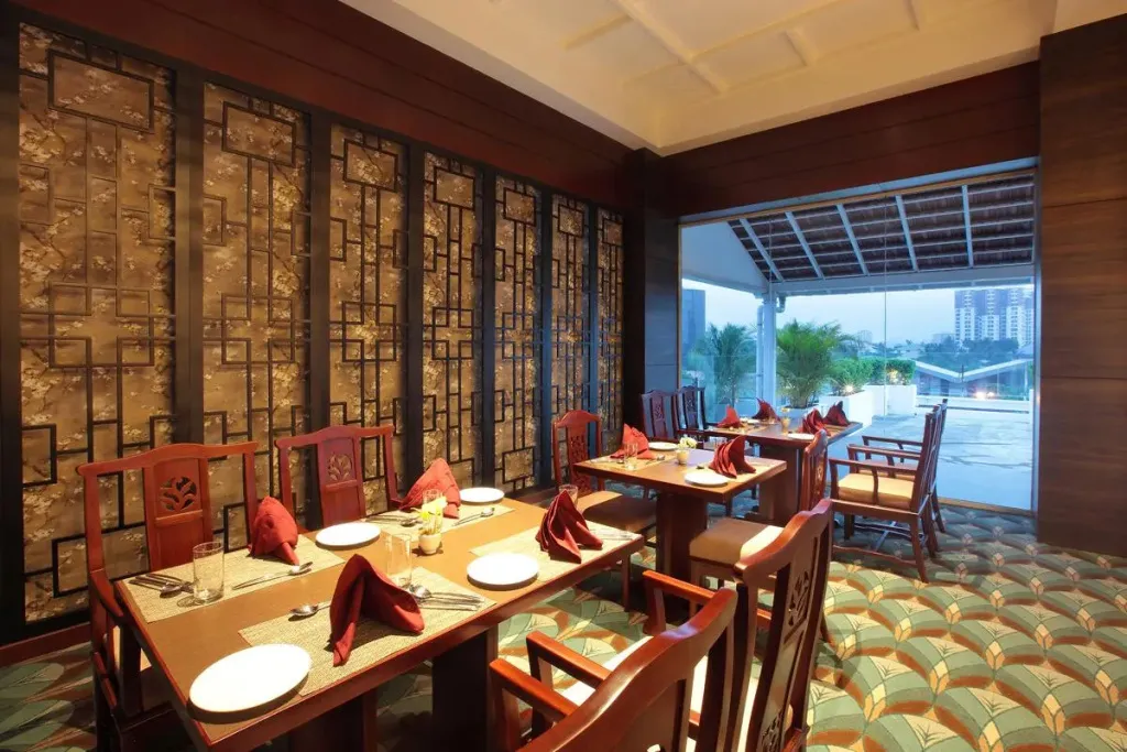 Une salle de restaurant lumineuse avec des tables dressées et une vue sur la ville.