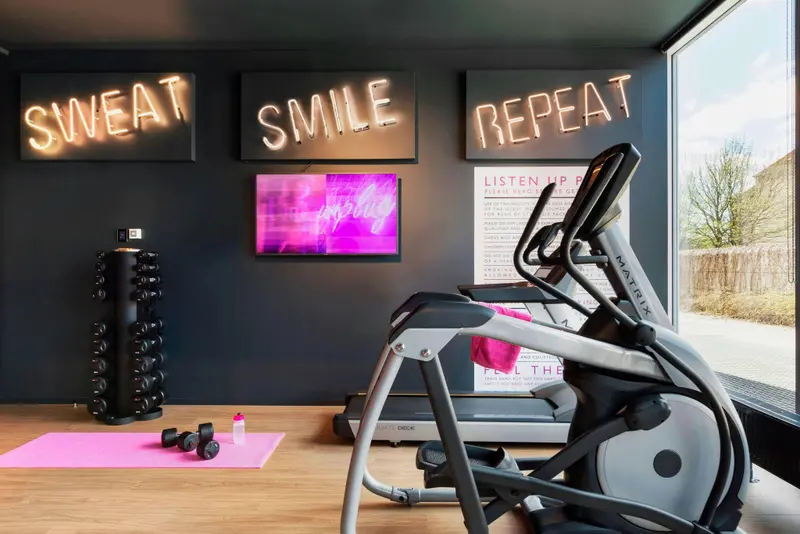 Une salle de sport lumineuse avec des équipements de fitness et des néons décoratifs.