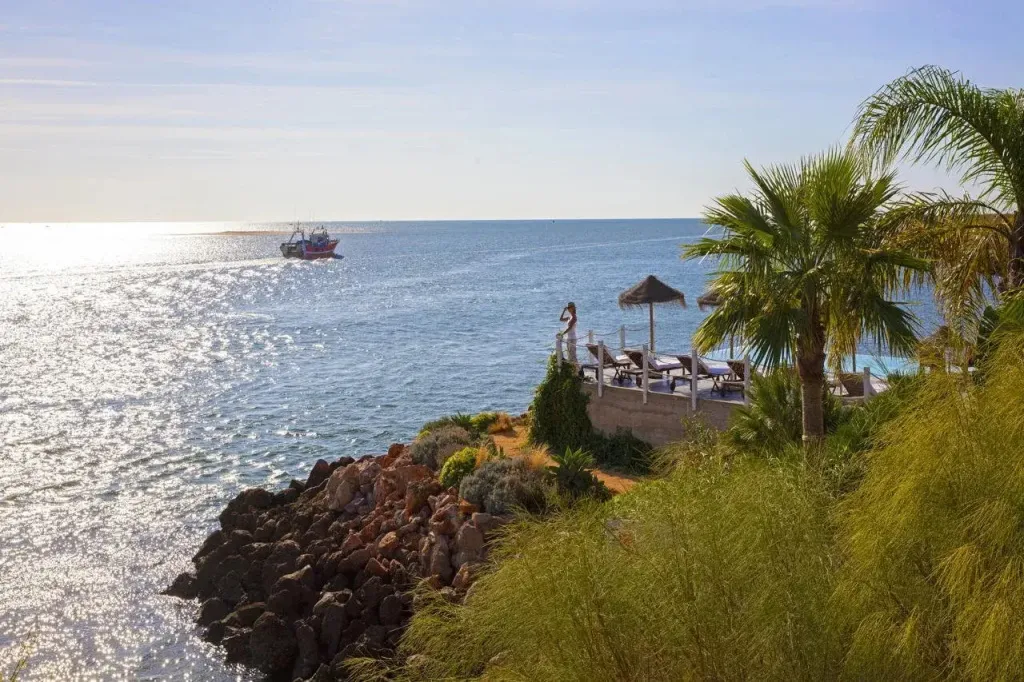 Vue sur la mer depuis une terrasse ensoleillée avec des transats.