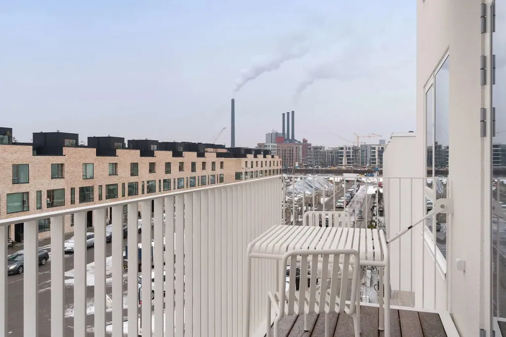 Vue d'une terrasse avec une rambarde blanche donnant sur un paysage urbain.