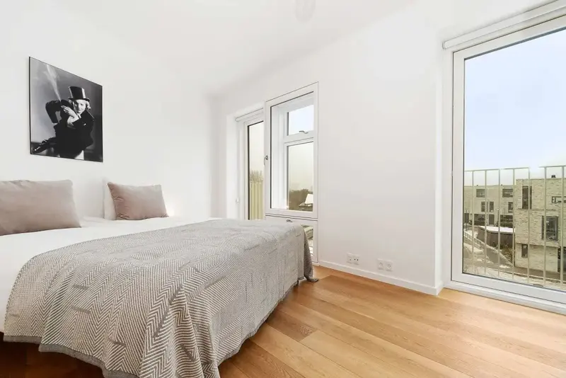 Une chambre lumineuse avec un lit simple et une vue sur la ville.