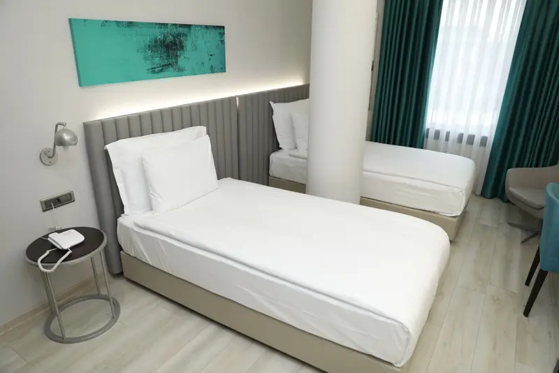 Une chambre d'hôtel lumineuse avec deux lits simples et une décoration sobre.