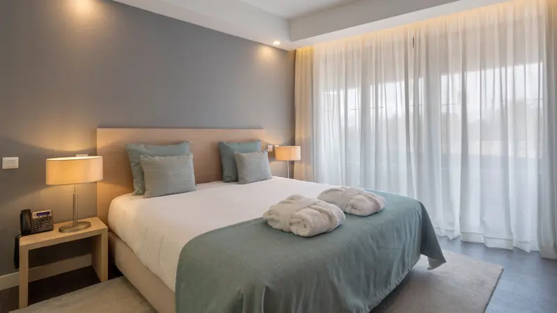 Une chambre lumineuse avec un grand lit recouvert d'une couette et de coussins.
