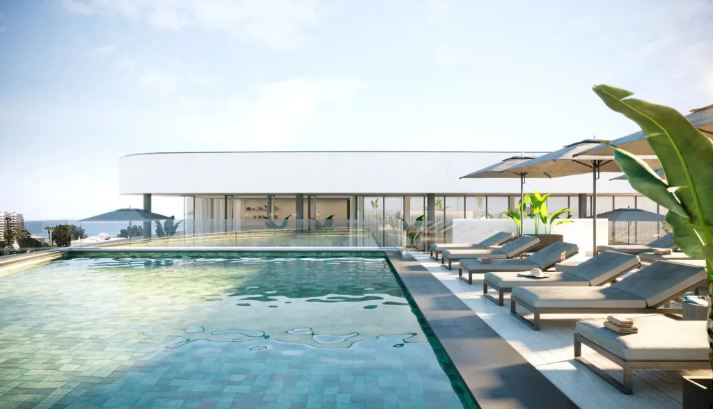 Transats et parasols bordent une piscine à débordement avec vue sur la mer.
