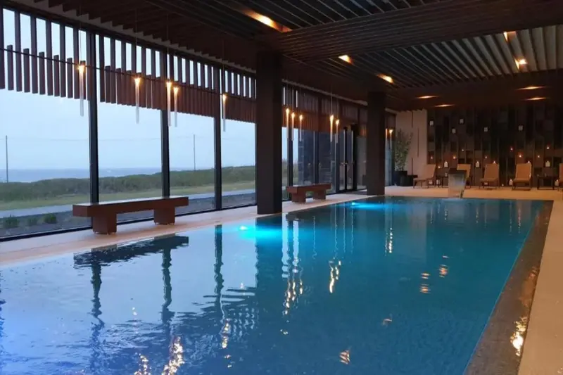 Une piscine intérieure lumineuse offre une vue sur un paysage extérieur.
