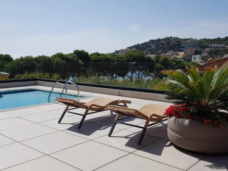 Terrasse avec transats et piscine au bord d'une vue sur la ville.