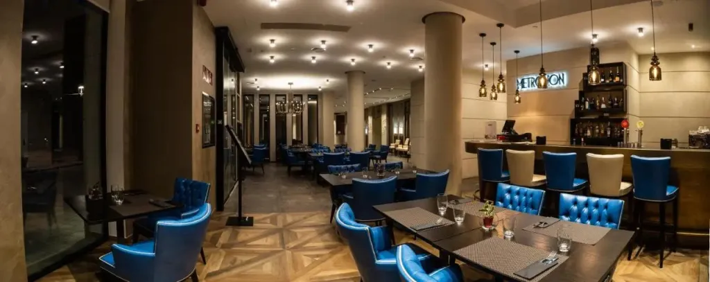 Une salle de restaurant lumineuse avec des tables dressées et un comptoir de bar.