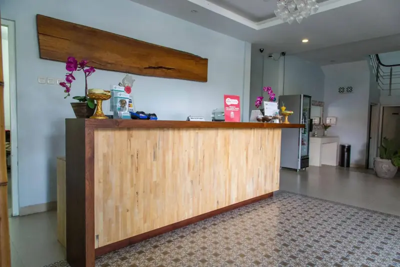 Un comptoir d'accueil en bois clair dans un hall spacieux et lumineux.