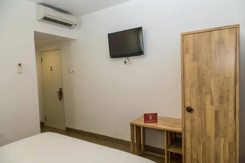 Une chambre lumineuse avec un lit et un meuble télévision.