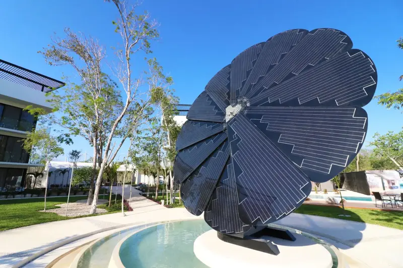 Une grande structure florale sombre se dresse au centre d'un jardin verdoyant.