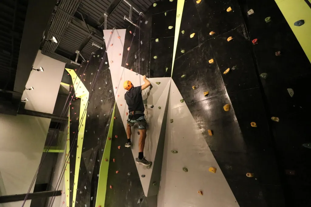 Un homme grimpe sur un mur d'escalade en intérieur.