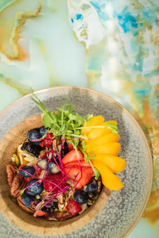 Un bol de fruits frais et de céréales est présenté sur une table.